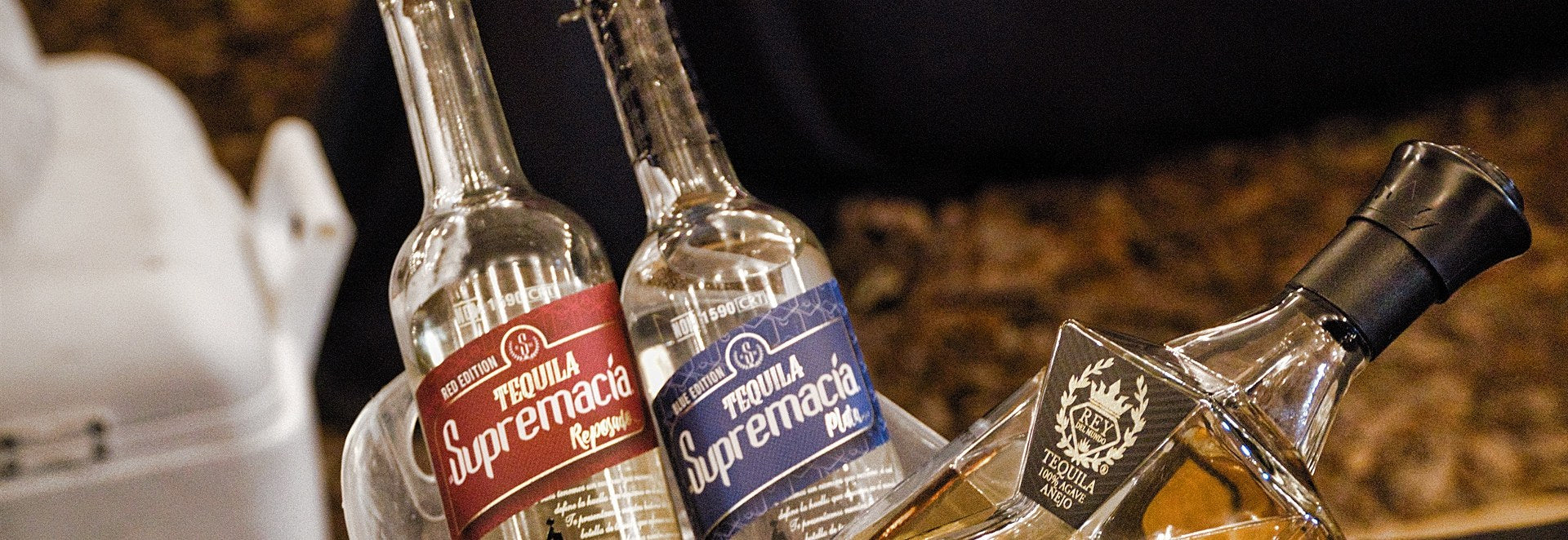 Bottles of La Supremacía Tequila Reposado and Plata chilling in an ice bucket at an event